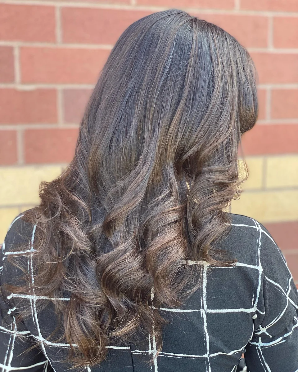 Dimensional brunette highlights styled in polished curls