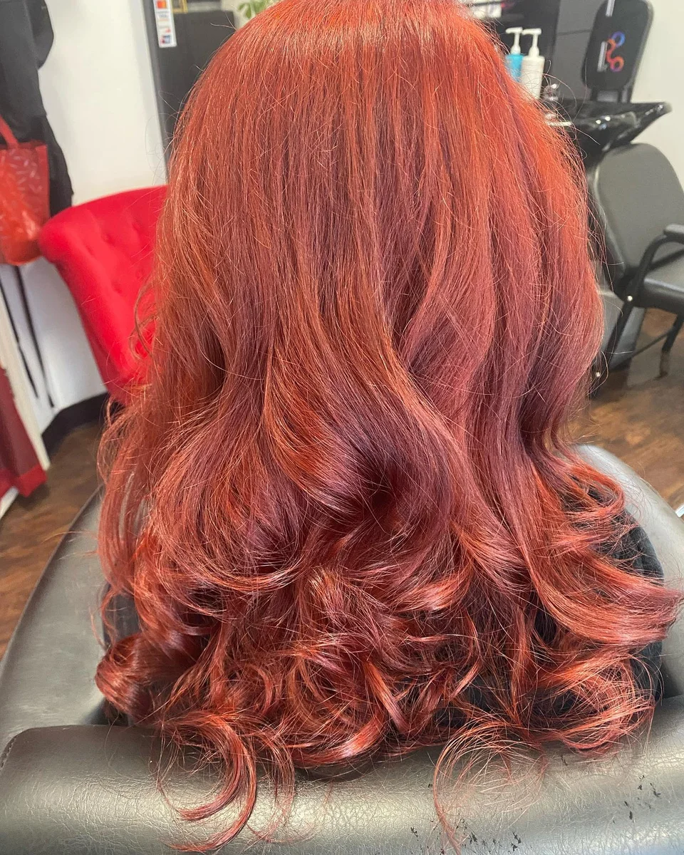 Vibrant copper-red hair styled in loose curls