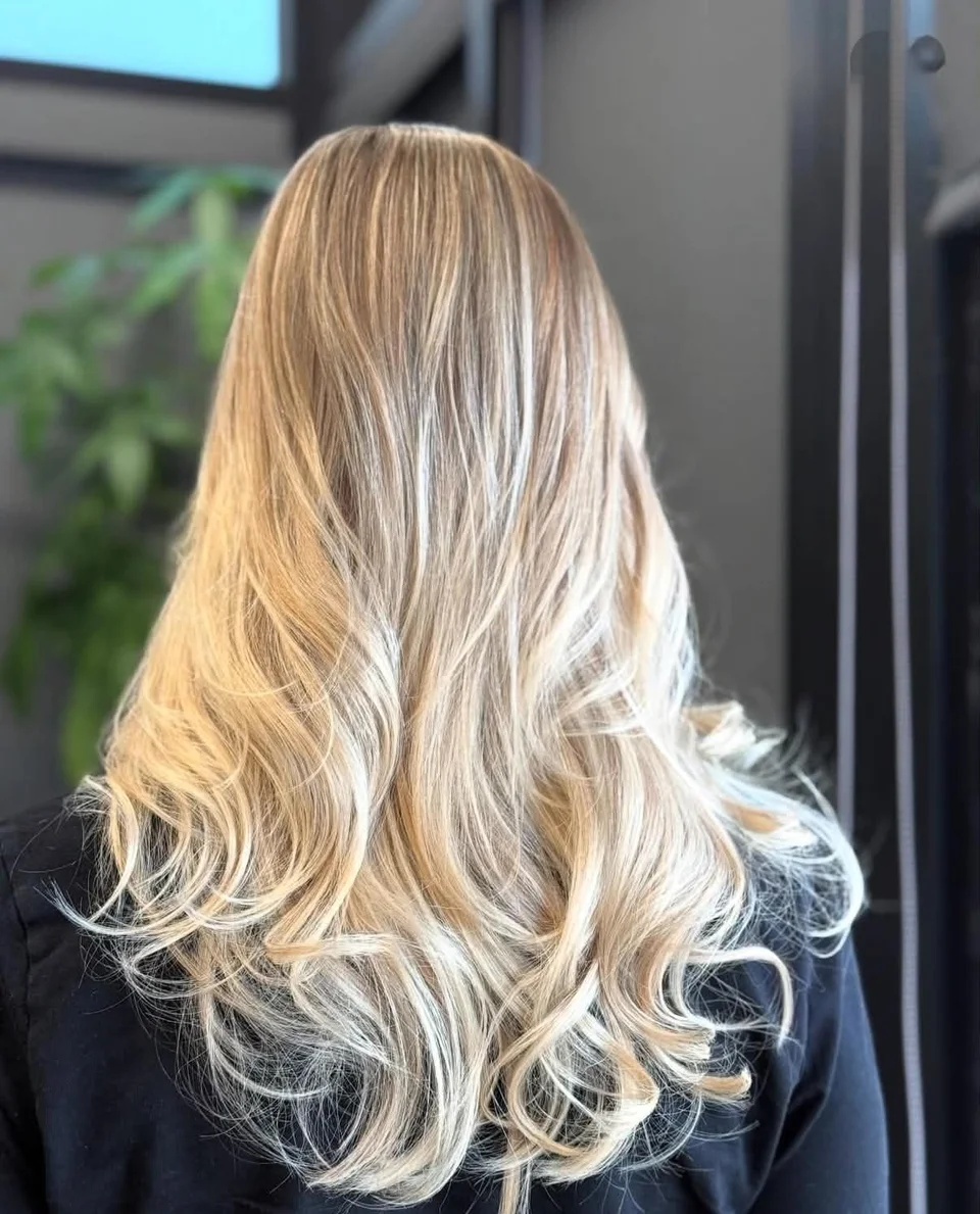 Long icy blonde balayage styled in polished curls