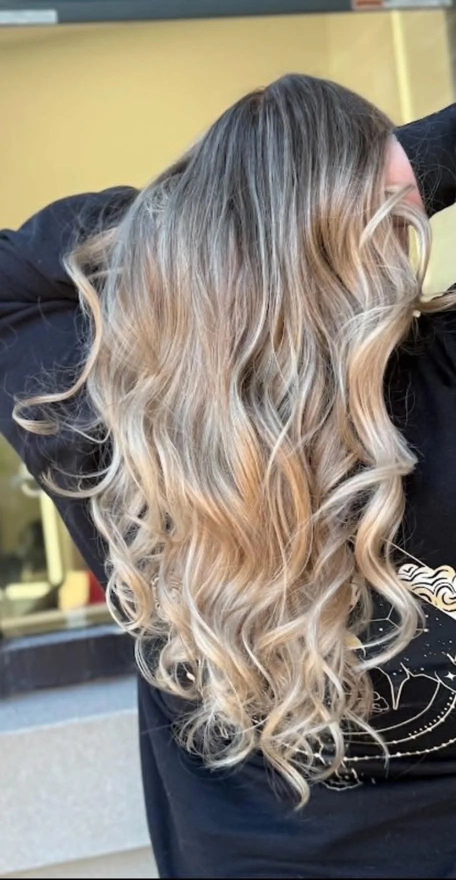 Long cool blonde balayage styled in soft curls