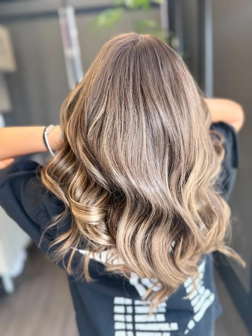 Shoulder-length beige blonde highlights styled in glossy waves