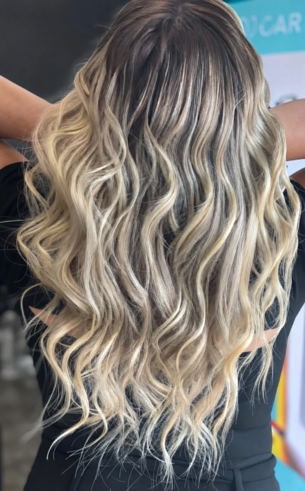 Dimensional blonde hair with a dark root styled in long waves