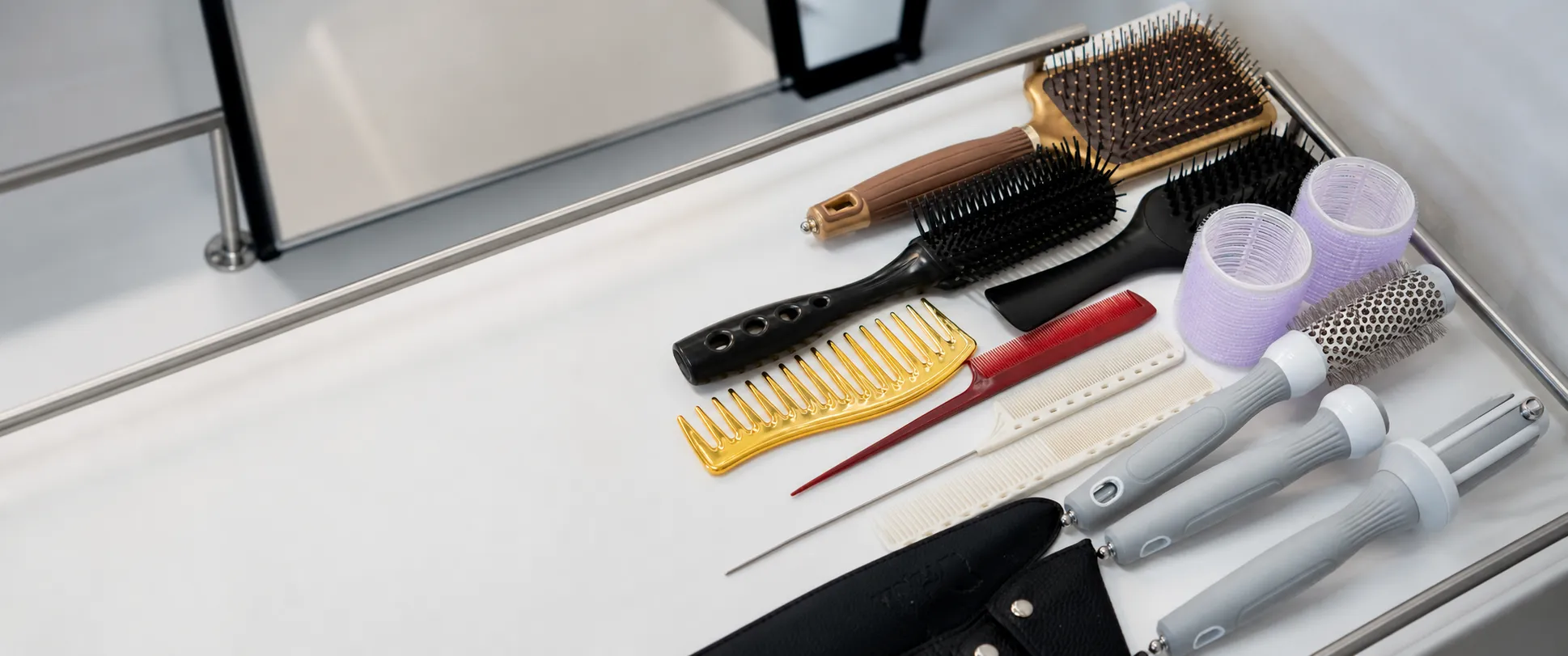 Professional salon brushes, combs, rollers, and styling tools arranged on a work tray