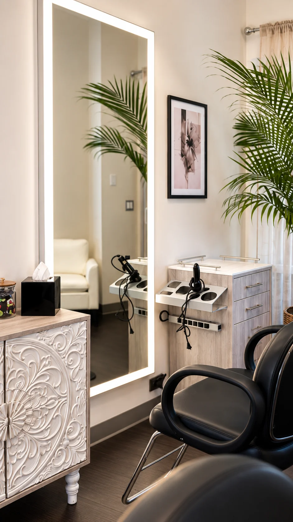 Illuminated mirror and black styling chairs beside a carved cabinet