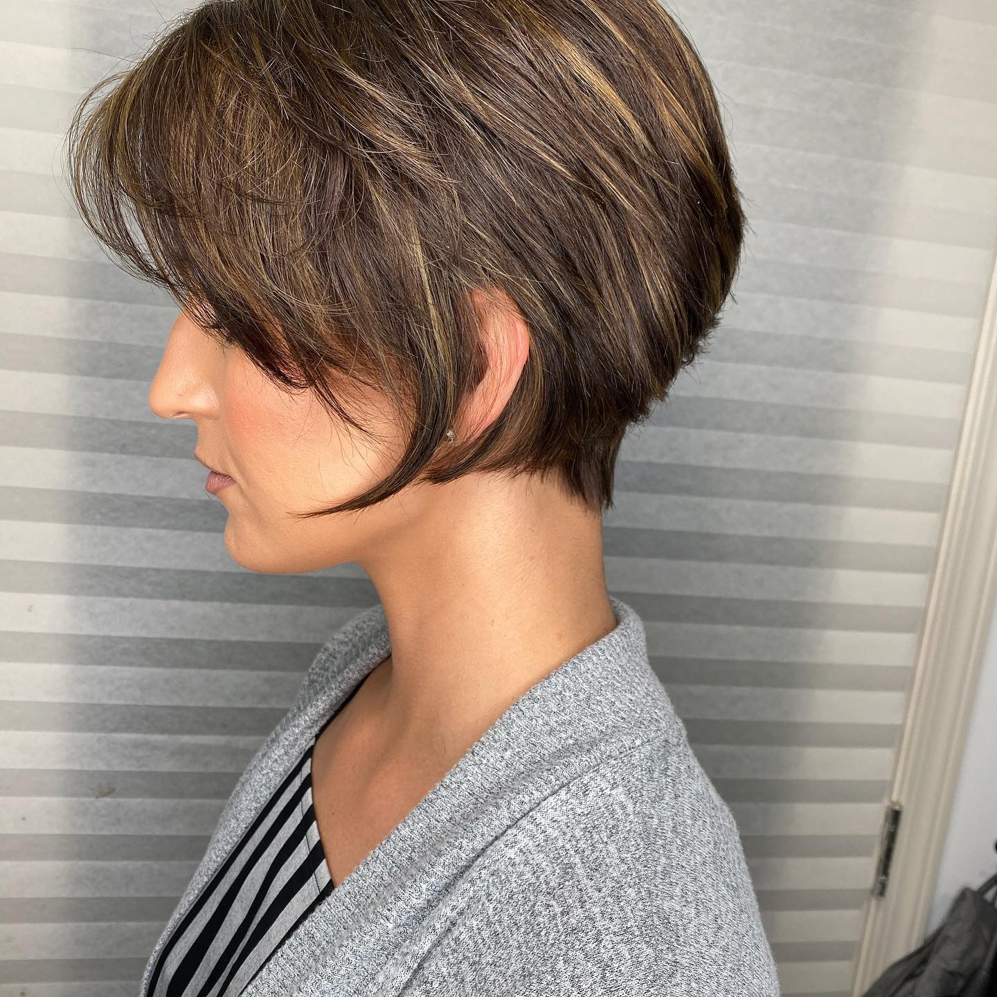 Textured brunette pixie haircut with caramel highlights