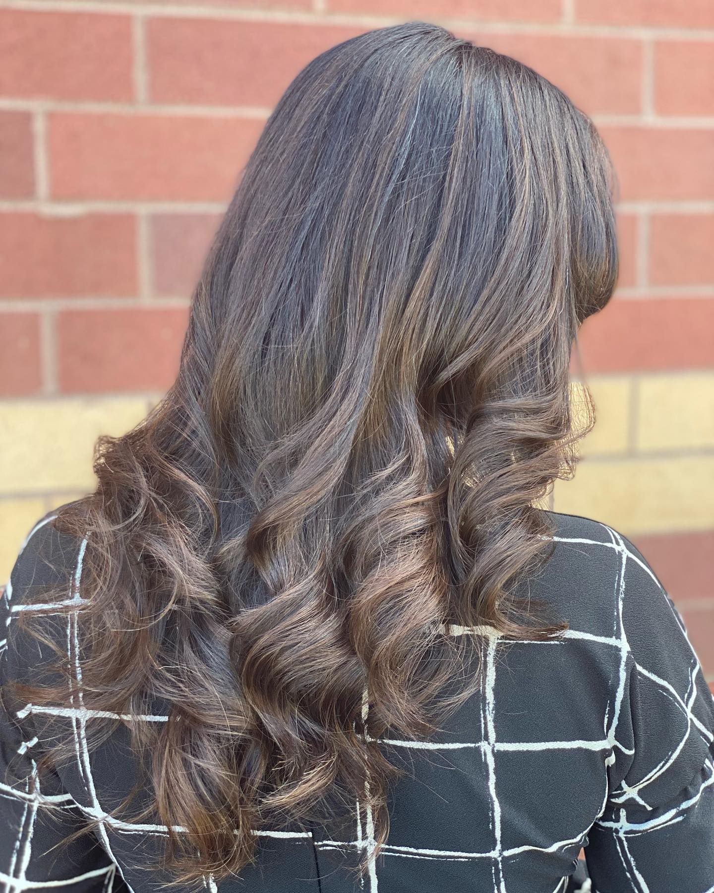 Dimensional brunette highlights styled in polished curls