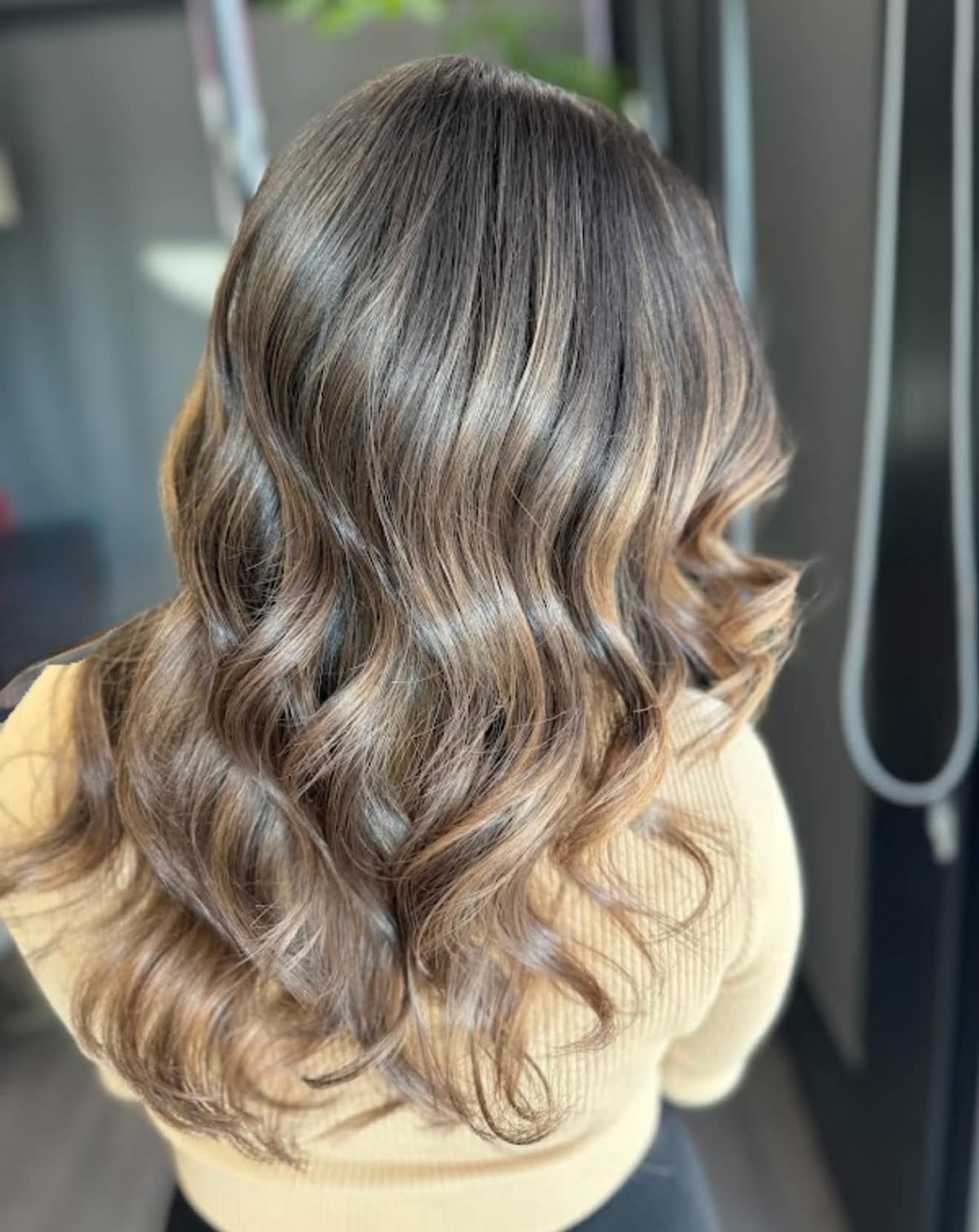 Dimensional brunette hair with caramel highlights styled in soft waves